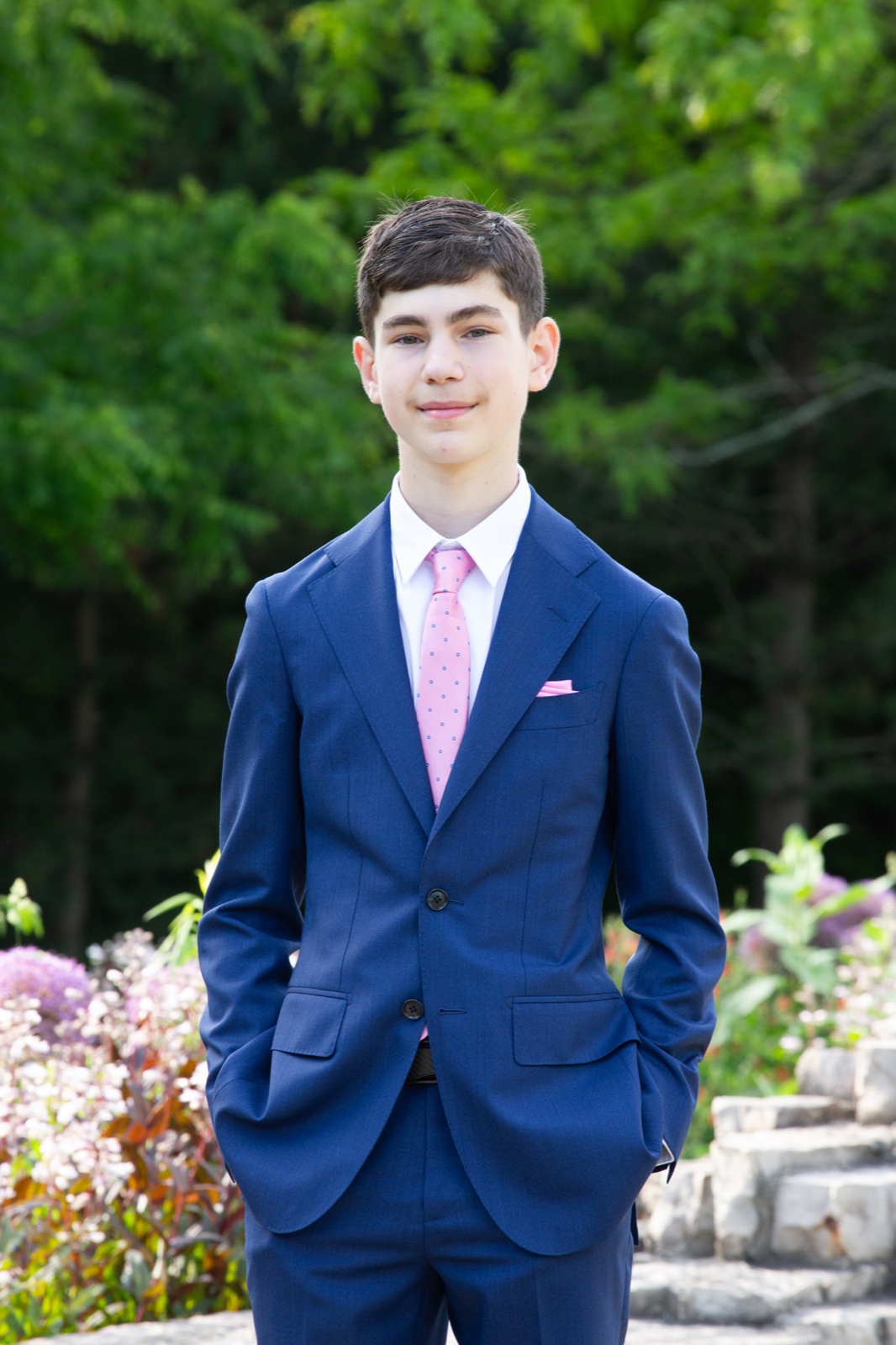 Evan Uster in a navy suit, standing in a garden